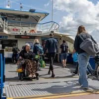 A person in an electric wheelchair exits the ferry.