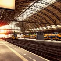 Platform of Amsterdam Central Station, with NS trains on the railways behind.