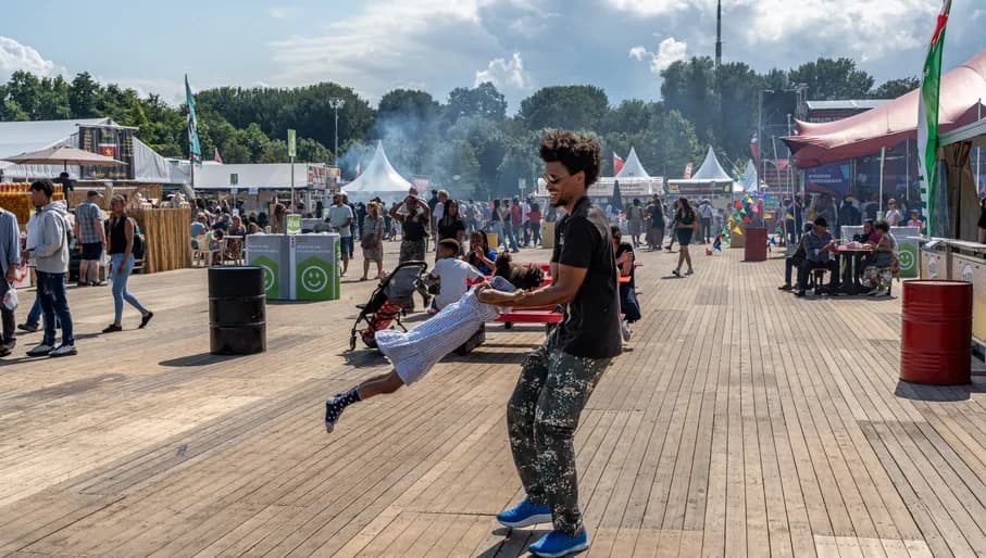 A father swings his daughter through the air at Kwaku Summer Festival 2023.