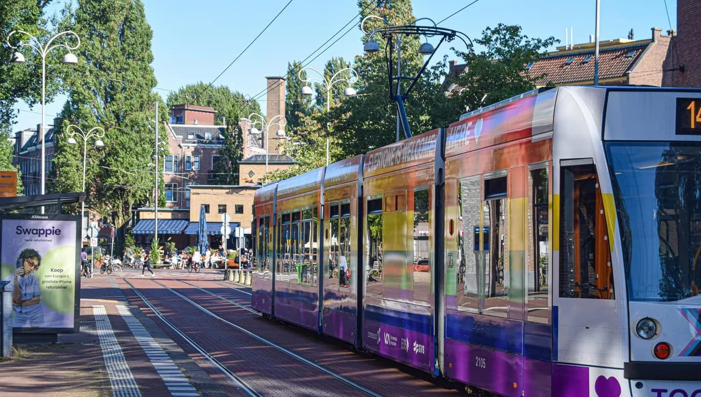 Colourful tram with Pride flag arriving at Javaplein.