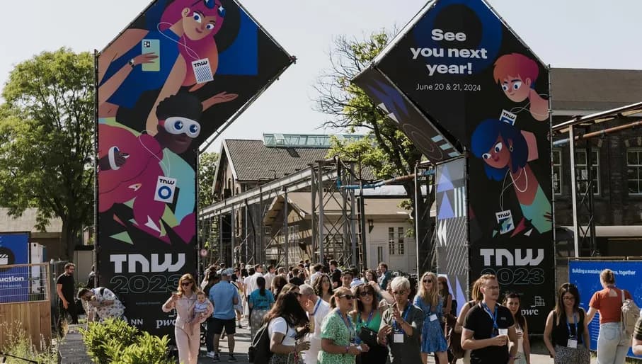 People talking and walking around TNW outdoor signs, The Next Web 2023 conference at Taets Art and Events Park