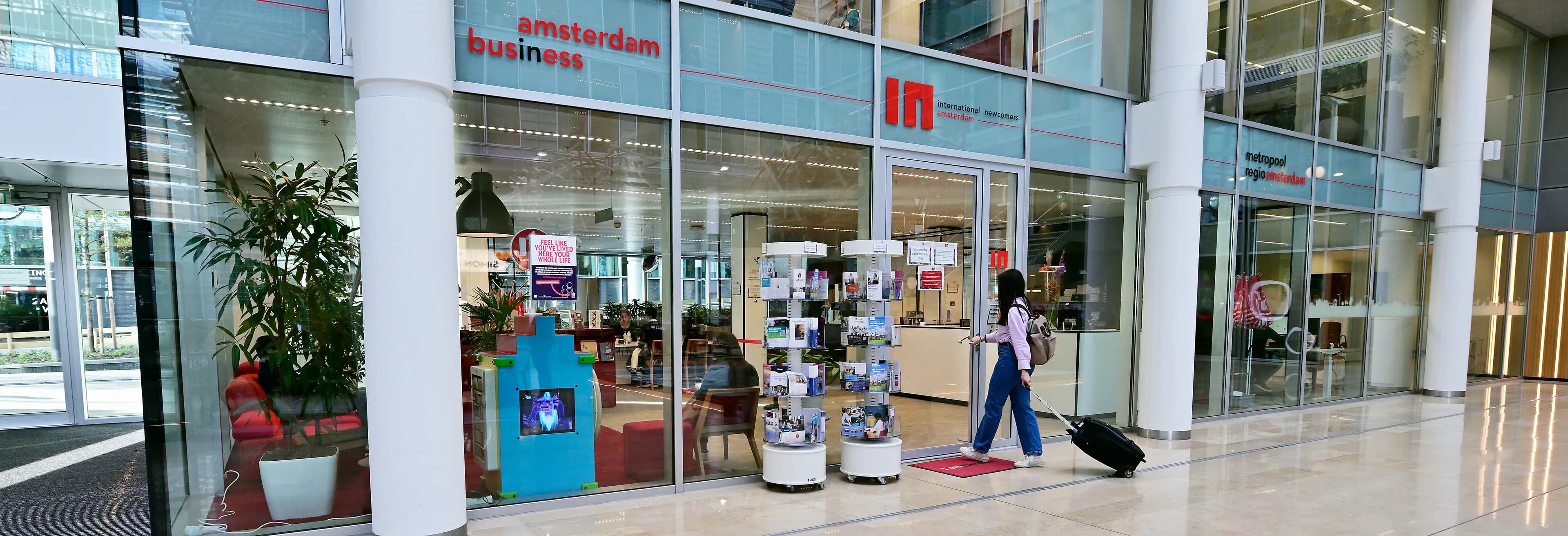 Woman with suitcase walking into the offices of INAmsterdam