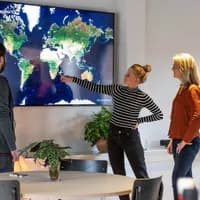 Polarsteps employees in their office pointing at a screen showing a world map.