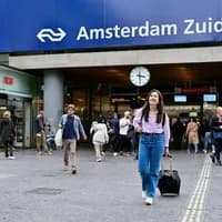 Women with suitcase in front of NS station Amsterdam Zuid