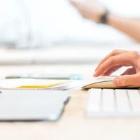 Close up of hand moving mouse next to laptop on desk.