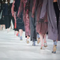 Models wearing violet and purple clothing on the catwalk during a fashion show.