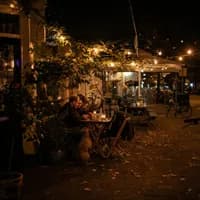 People sitting on terrace at night at Compartir wine bar and restaurant on Spaarndammerstraat