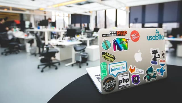 Laptop with Startup Amsterdam sticker and other stickers on desk in office