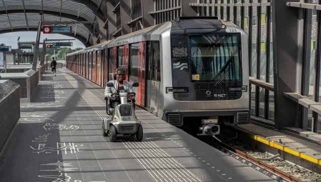 A person in an electric wheelchair riding on the metro platform.