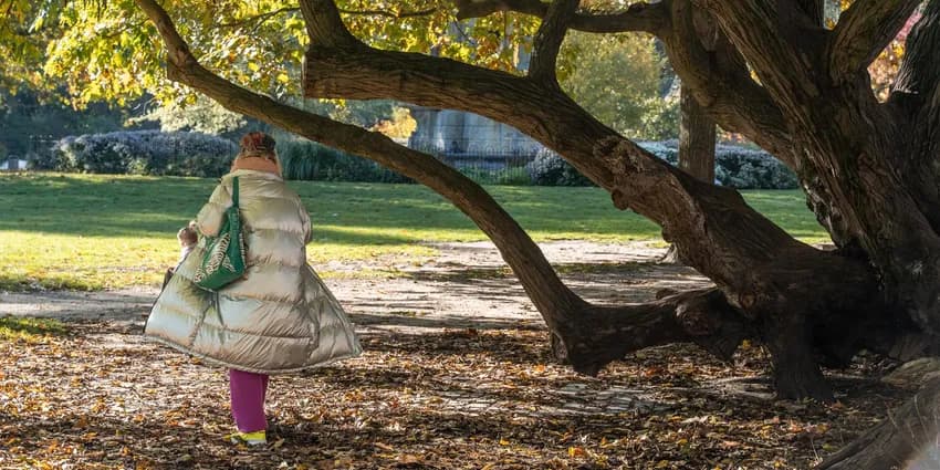 A person walking through the Sarphatipark on a sunny autumn day.