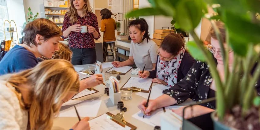 People taking a Calligraphy workshop writing on a clipboard paper holder
