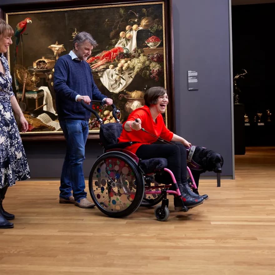 Happy woman in a wheelchair and a dog, visiting Rijksmuseum