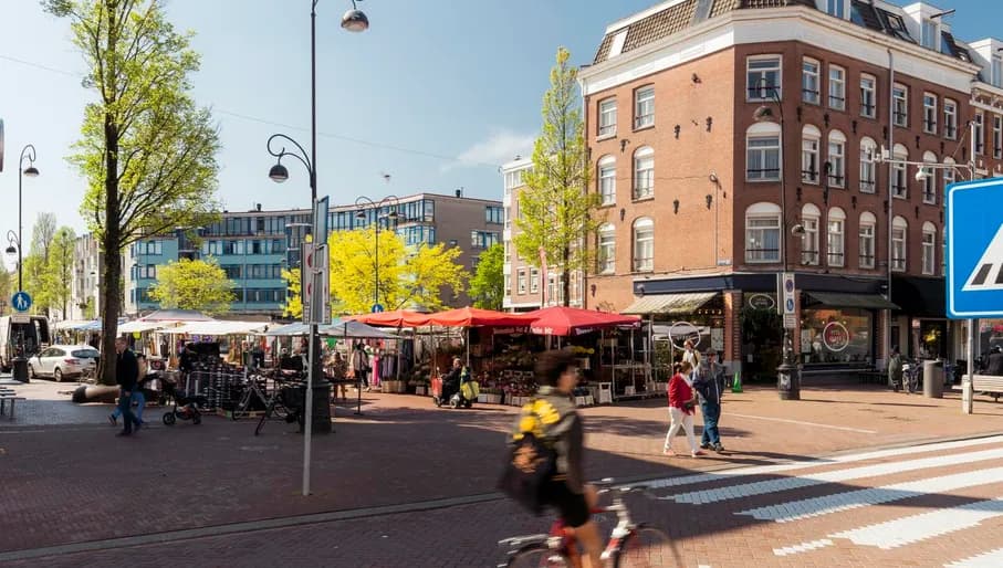 A cyclist on the crossing of Eerste van Swindenstraat and Dapperplein with some Dappermarkt market stalls.