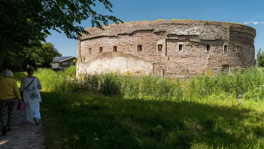 A couple walking alongside Fortress Uitermeer, part of the Defense of Amsterdam.