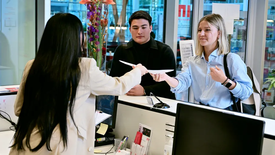 Man and women in front of desk at the INAmsterdam offices, seen from the front, employee seen from the back