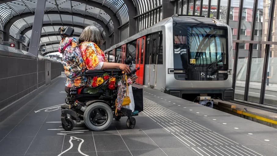 A person in an electric wheelchair waiting for the metro.