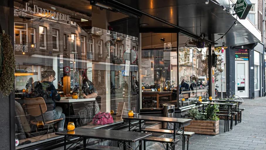 Women dining in the window and street terrace of Fa. Pekelhaaring on Van Woustraat