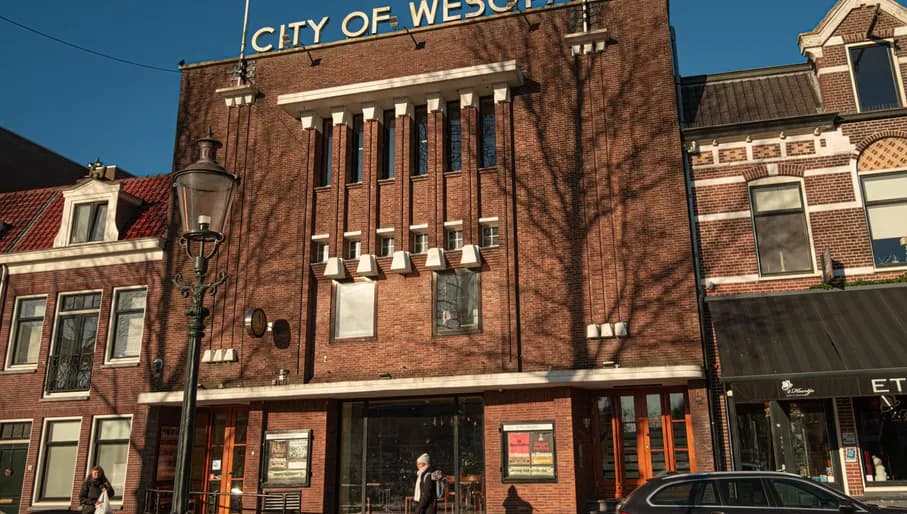 Woman walking past City of Wesopa cinema in Weesp