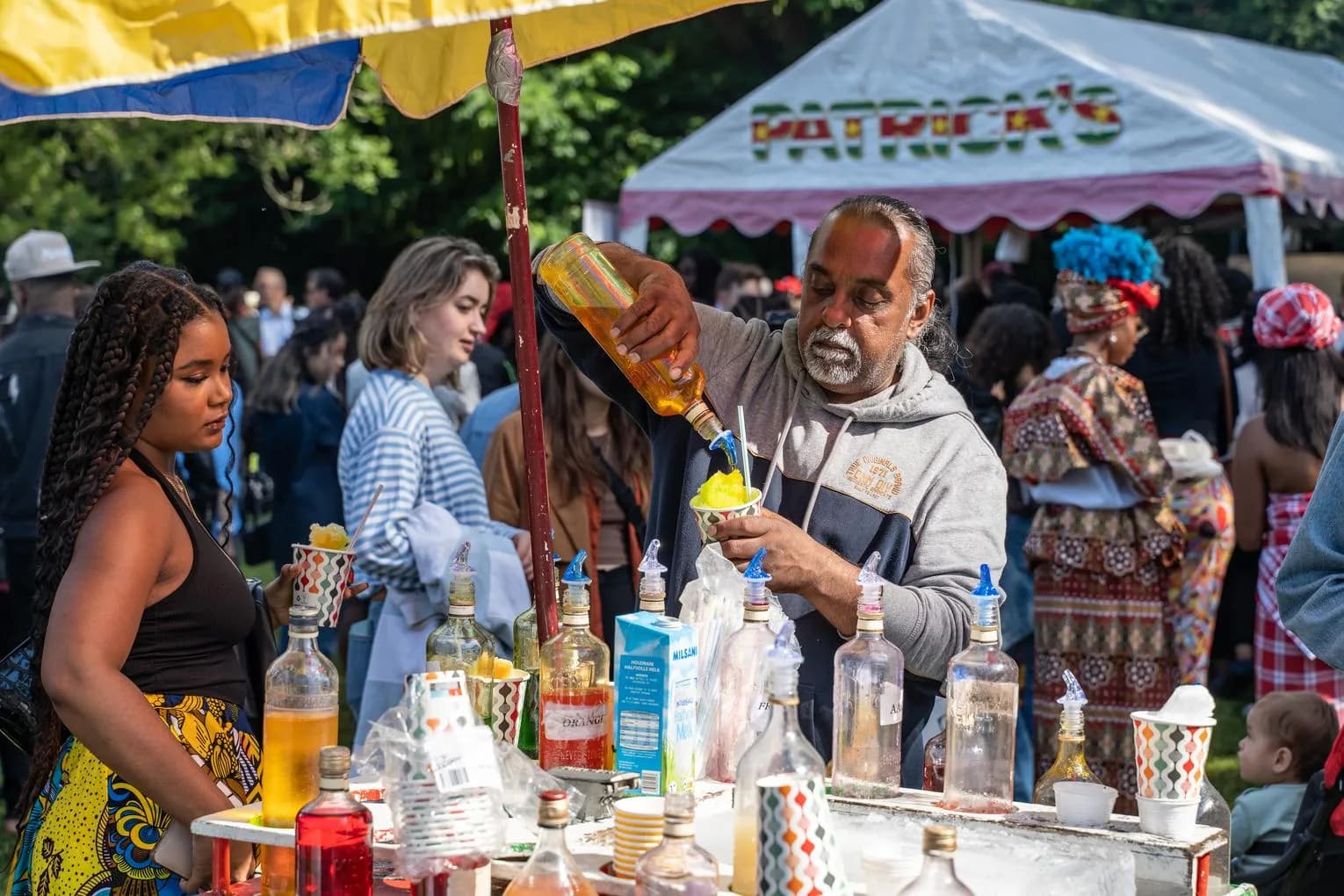 A man preparing so called 'schaafijs' (shaved popsicle) during Keti Koti Festival 2022 in the Oosterpark.