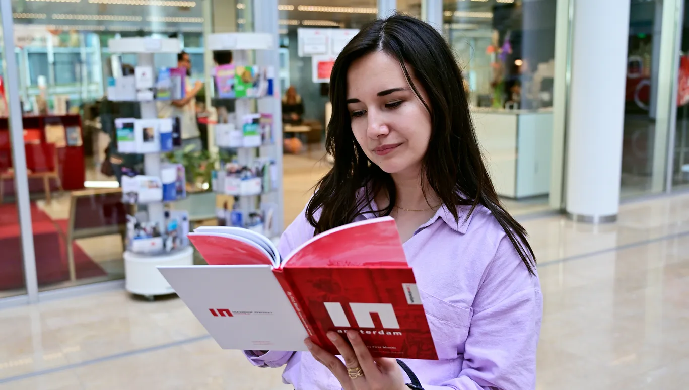 Woman reading INAmsterdam booklet in front of INAmsterdam offices