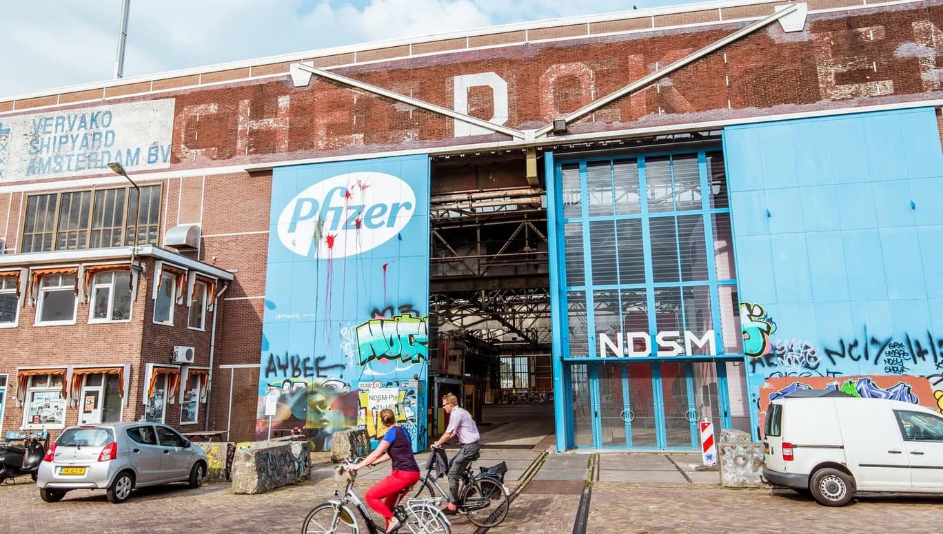 People cycling past IJhallen Pfizer Doors