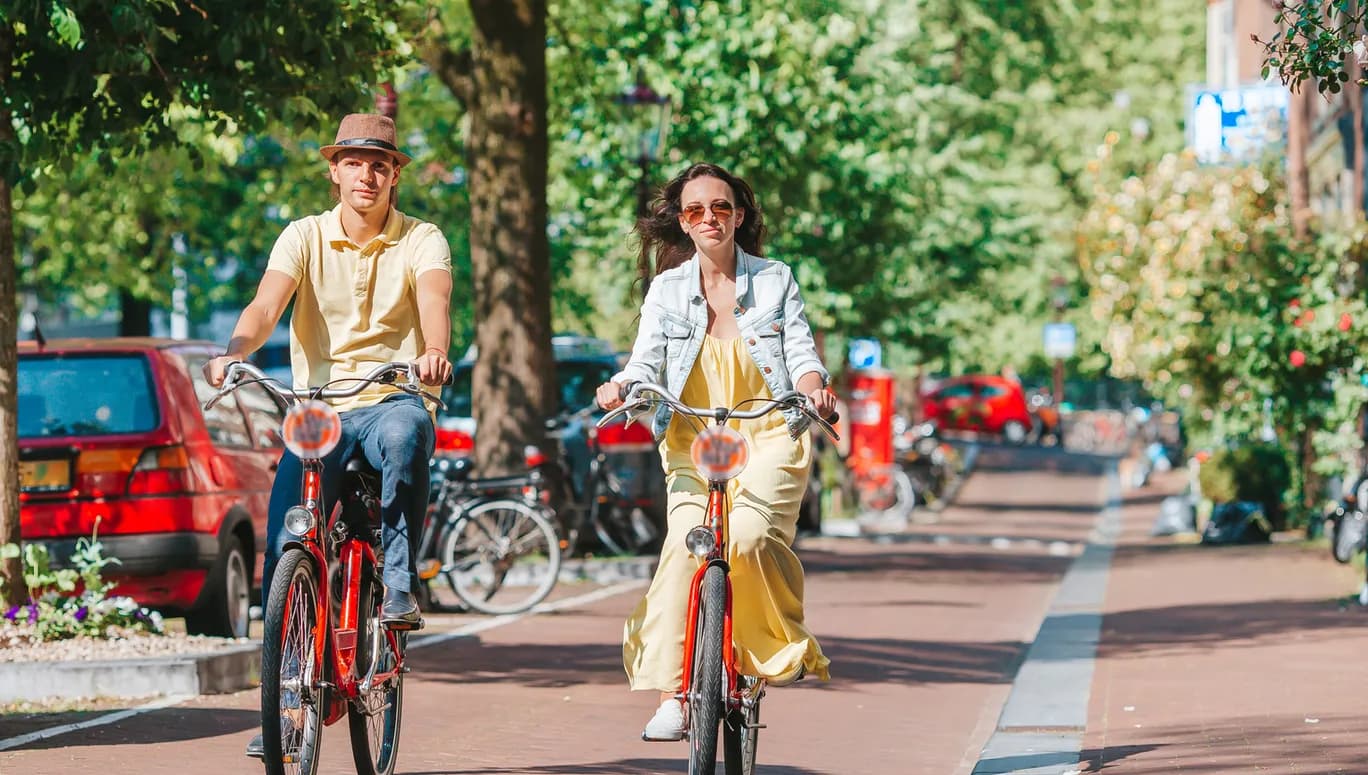Young happy couple on red bikes cycling on the old streets in the city centre.