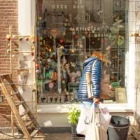 Woman with shopping bags looking in the window of Sjakies gift and concept store on shopping street. Haarlem Content Creation Day March 2024