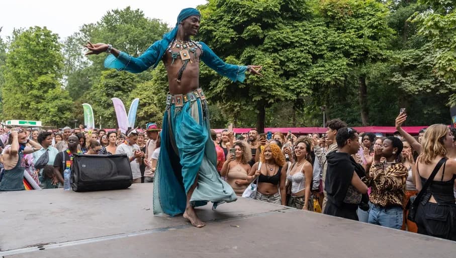 A crowd of people watching a man in a costume performing - Pride park festival