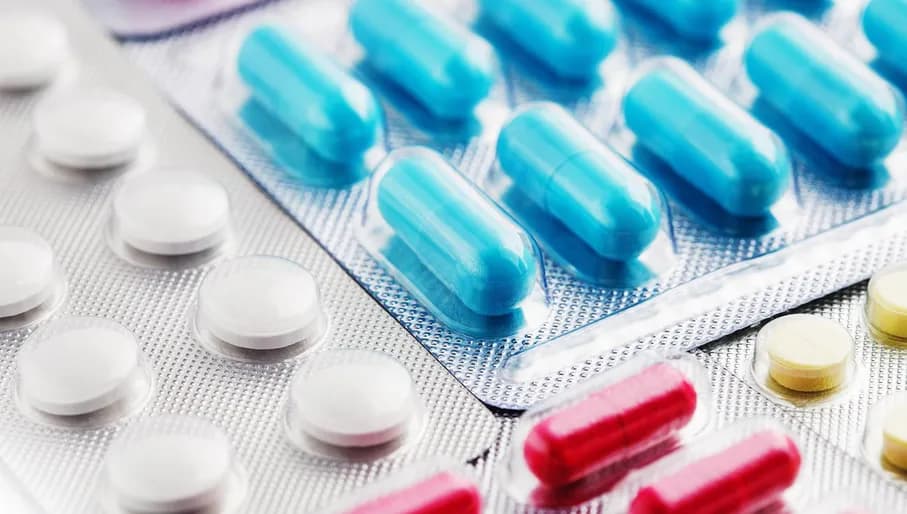 Heap of medical pills in white, blue and other colors. Pills in plastic package. Concept of healthcare and medicine.