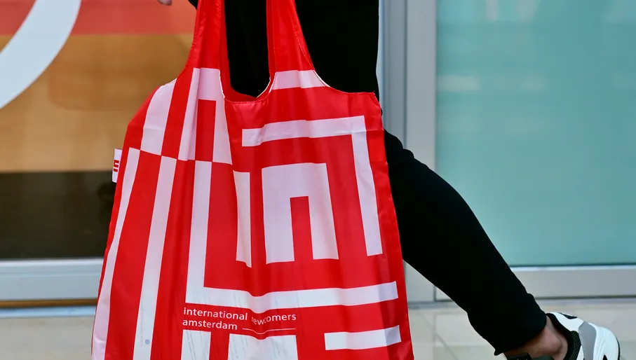 Woman walking with INAmsterdam merchandise tote bag close up